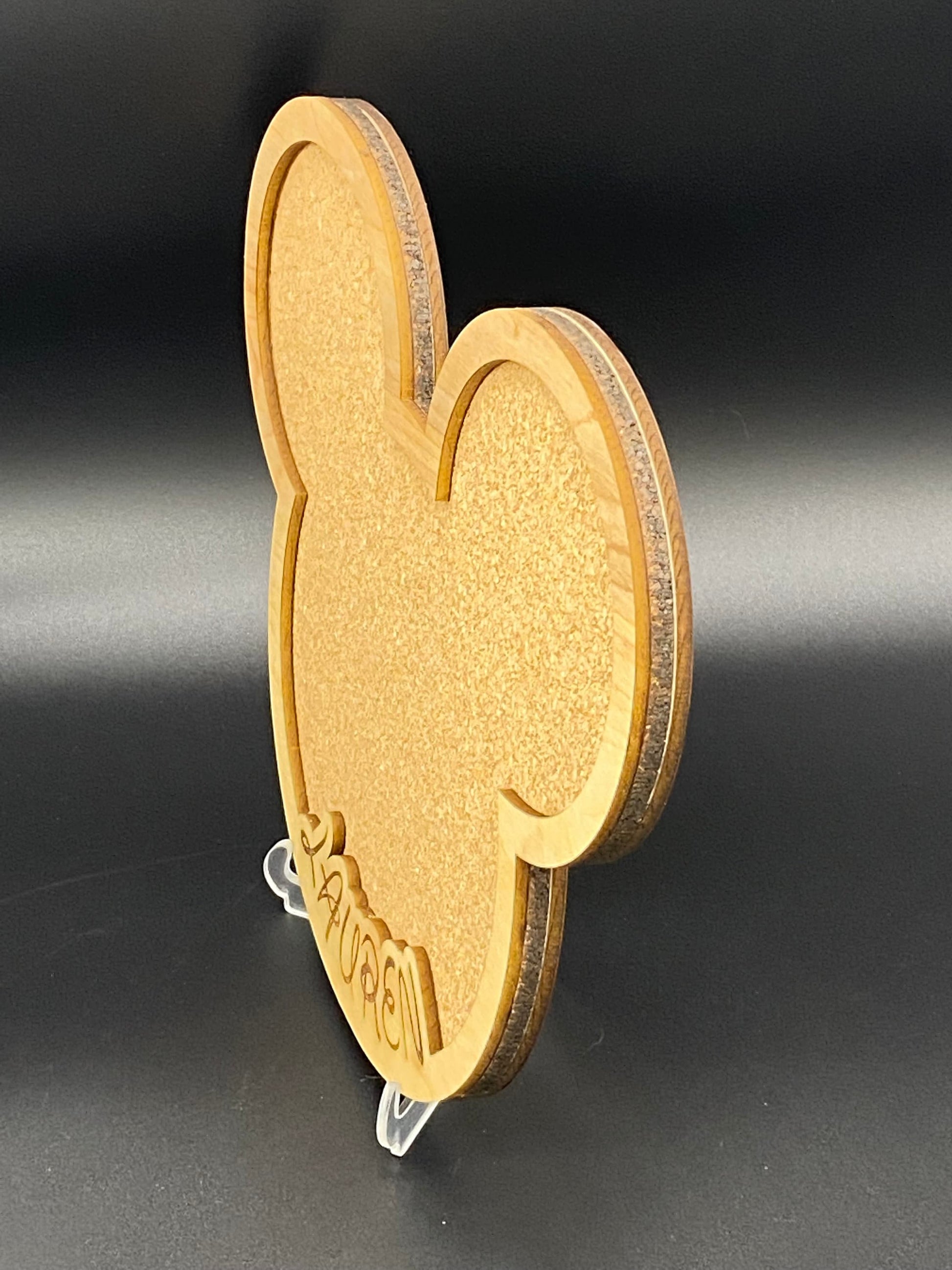 Freak of Laser personalized character-shaped cork pin display board with custom wood engraving on a clear stand.